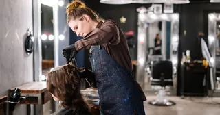Hair stylist styling a client's hair in a salon